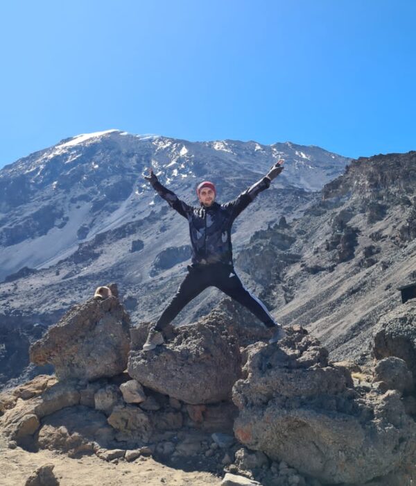 Man standing on rocks during happy with his Kilimanjaro hike