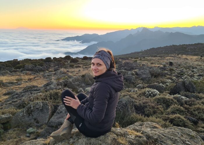 A Woman sitting on Kilimanjaro and watching a beautiful sunset during the best Kilimanjaro hiking month